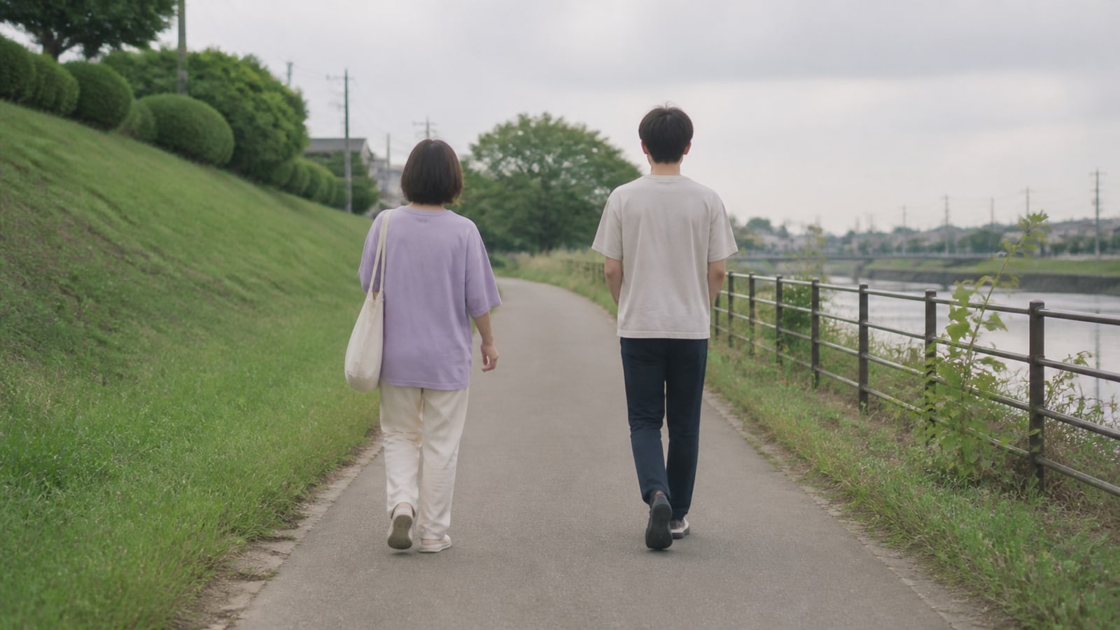 川沿いの道を、少し距離を空けて同じ方向へ歩く親子の後ろ姿のイメージ